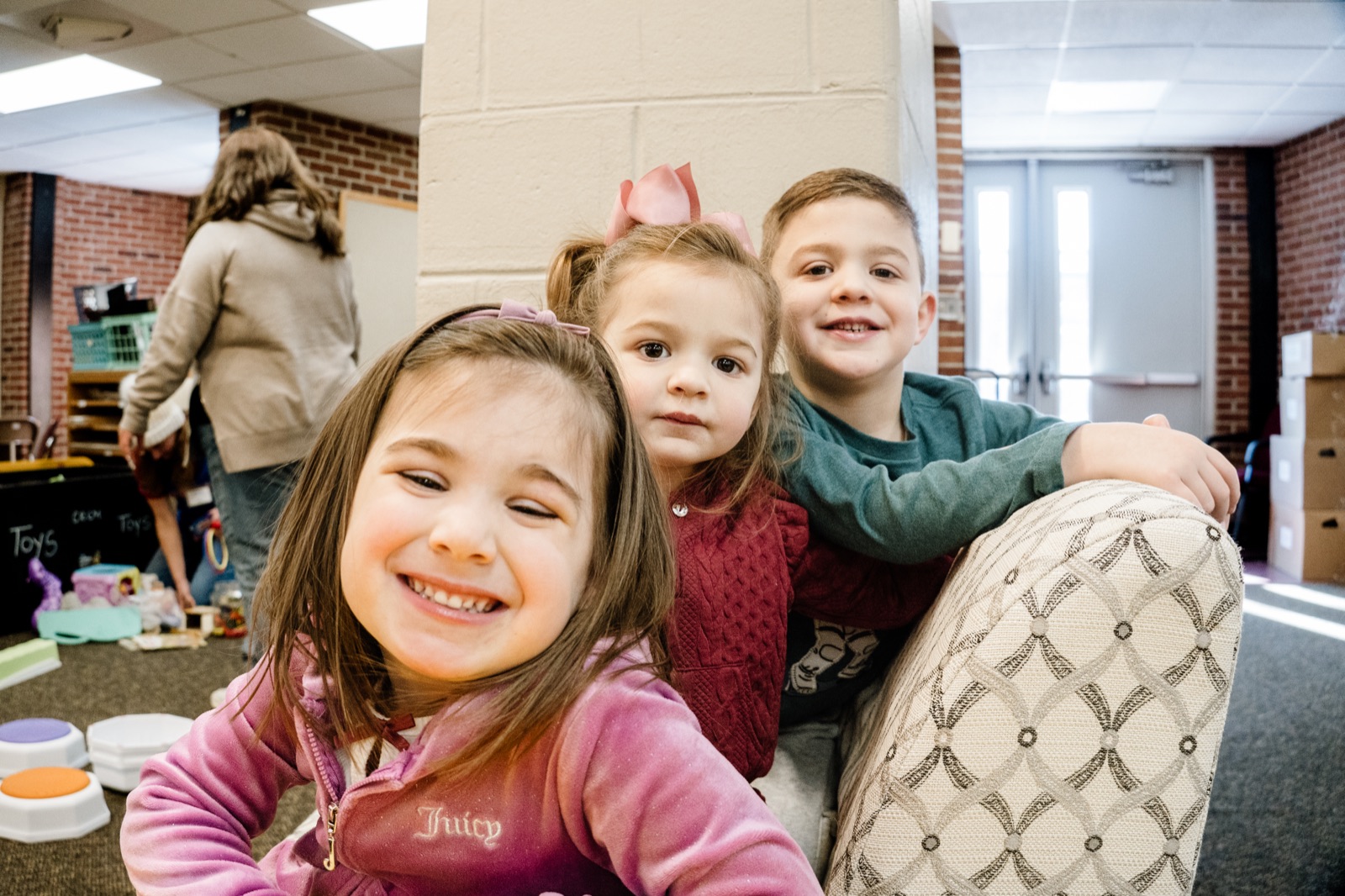 Three preschool children smiling together at CRWC Kidz